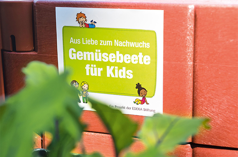 Das Logo von Gemüsebeete für Kids auf einem Hochbeet